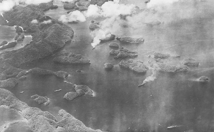 attack on palau-08.JPG - Iro (right centre) is on fire with smoke rising from its aftship. Directly left of Iro is the Nagisan Maru (anchored in the small bay). Kamikaze Maru (above centre) is smoking heavily and the Sata (bottom right) is sinking by the stern.